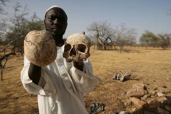 ▲ 다르푸르 학살에서 살아남은 사람이 여기저기 나뒹구는 희생자의 해골을 들어보이고 있다.