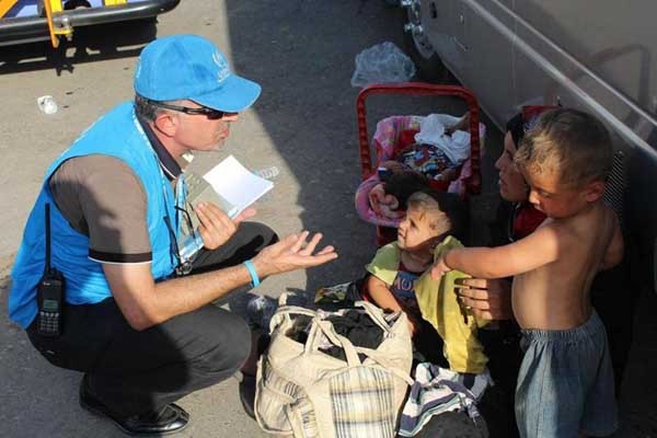 ▲ 어린 아이들과 피란 중인 여성에게 설명하는 유엔 직원. [사진: 유엔 난민고등판무관실]
