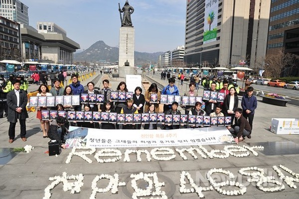 ▲ 24일 오후 서울 광화문 광장 이순신 동상 앞에서는 청년들이 국화꽃을 하나둘 바닥에 내려놓느라 분주했다. 그 옆으로는 경건한 표정을 지은 다른 청년들이 또래 친구들의 사진을 들고 서 있었다ⓒ뉴데일리 이미화 기자