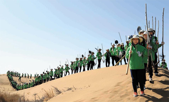▲ [남의 사막화]를 성공적으로 막은 대한민국의 기적은 이제 황사의 발원지인 중국의 사막화 방지에도 힘을 보태고 있다. 20014년 3월30일. 중국 네이멍구 쿠부치 사막 모래언덕에서 한국의 미래숲 녹색봉사단으로 참여한 대학생들이 한손엔 심을 나무를, 한손엔 삽과 양동이를 들고 이동하고 있다. 이들은 이틀 동안 중국 현지 봉사단과 함께 나무 4400그루를 심었다. /미래숲 제공ⓒ  [출처] 본 사진과 설명은 조선닷컴에서 가져왔습니다.