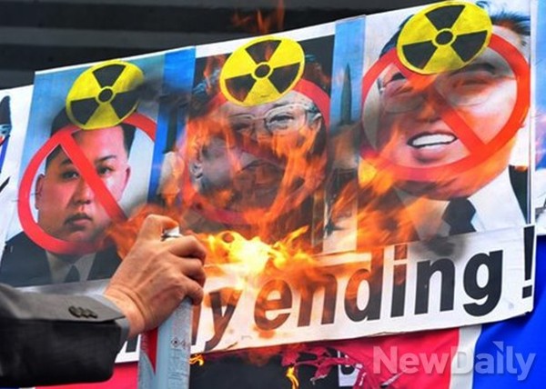 ▲ 김일성 생일인 15일, 서울 광화문 광장에서 한 회원이 김씨 일가의 사진과 북한 인공기 위에 불을 붙이고 있다. ⓒ 뉴데일리 이미화 기자