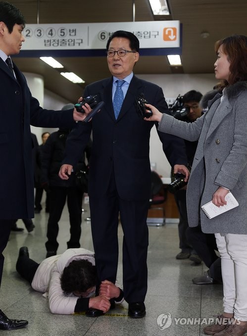 ▲ 저축은행에서 불법 자금을 받은 혐의로 기소된 박지원 새정치민주연합 의원이 서초구 서초동 서울고등법원에서 열린 첫 공판에 출석하기 전 기자들의 질문에 대답하고 있다. 한 저축은행 피해자가 대답하는 박지원 의원의 다리를 붙잡고 억울함을 호소하고 있다. ⓒ연합뉴스