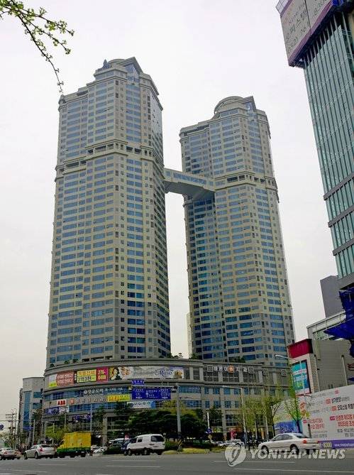 ▲ 울산시 남구 삼산동의 한 주상복합아파트. 이 건물은 미분양 해소를 위해 준중형 승용차 20대를 내걸어 눈길을 끌었다.ⓒ연합뉴스