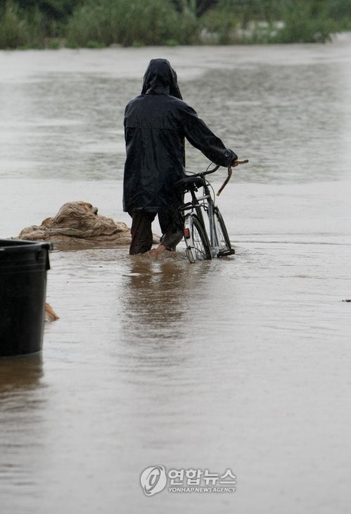 ▲ 2009년 7월 7일 영.호남 지역에 시간당 최고 100㎜ 이상의 기록적인 비가 내려 농경지와 가옥이 침수 또는 붕괴 되는 등 큰 피해가 발생했다. 사진은 광주 남구 대촌동에서 한 농부가 위태롭게 자전거를 끌고 침수된 논으로 걸어가는 모습.   [사진=연합뉴스]