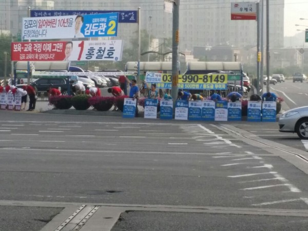 29일 김포 고촌사거리에서 파란색의 옷을 맞춰 입고 파란 피켓을 든 사람들이 '기호 2번'을 상징하는 제스처를 하면서 자칭 '투표 독려 운동'을 하고 있다. ⓒ홍철호 후보 선거사무소 제공