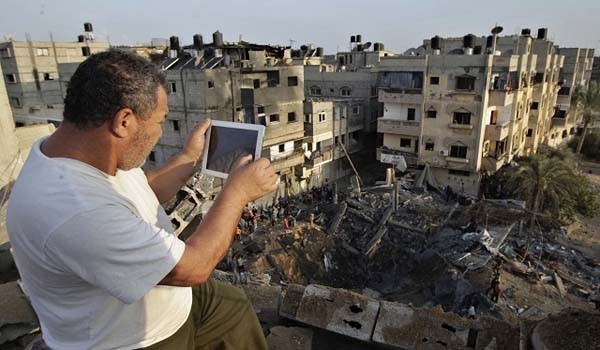 ▲ 이스라엘 방위군의 공습으로 무너진 건물을 찍고 있는 가자 지구 주민. [사진: 알 아라비야 보도화면 캡쳐]