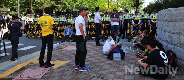 ▲ 여야의 세월호특별법 합의에 항의하기 위해 8일 오전 여의도 국회 향하던 세월호 가족대책위 차량이 경찰에 저지 당하자 유족들이 밖으로 나와 앉아 있다. ⓒ 뉴데일리 이종현 기자