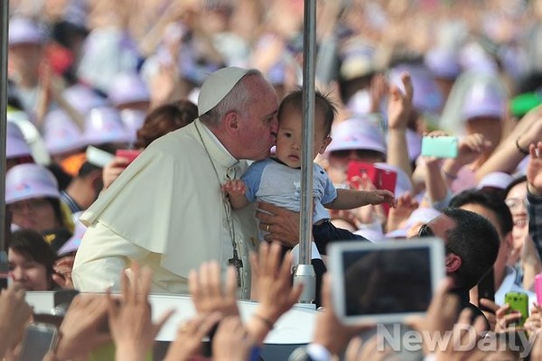 ▲ 프란치스코 교황이 16일 오전 서울 광화문에서 시복식을 집전하기에 앞서 카퍼레이드를 벌이다 어린이의 볼에 축북의 키스를 하고 있다.ⓒ정재훈 기자