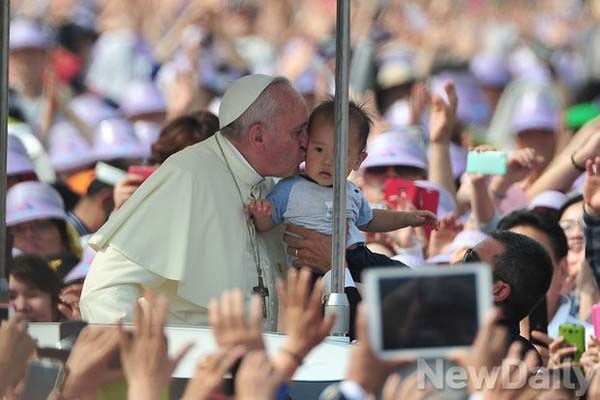 ▲ 지난 16일 서울 광화문 광장에서 열린 시복식에서 아이에게 입맞추는 프란시스코 교황 ⓒ뉴데일리