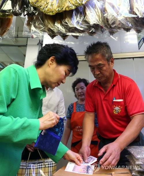 박근혜 대통령이 22일 부산 자갈치시장을 방문, 한 건어물 상점에서 물건을 산 뒤 온누리상품권으로 지불하고 있다.ⓒ연합뉴스