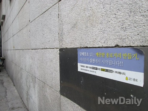 서울 광화문광장 인근 할리스커피숍(뒷편) 외벽에 "담배꽁초를 버리지 말라"는 경고 문구가 붙어 있다. 담배꽁초나 껌종이 등을 무단 투기할 경우 5만원의 과태료가 부과된다는 메시지도 보인다. ⓒ 뉴데일리
