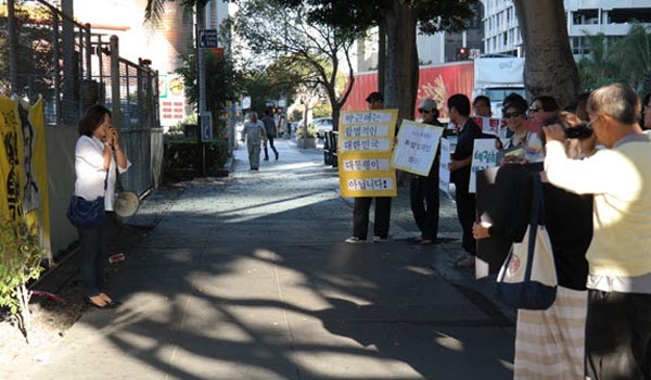 지난 20일(현지시간), 美LA 총영사관 앞에서 박근혜 퇴진촉구 시위를 벌이고 있는 시위대. 왼쪽 마이크를 든 여성이 미시USA 회원인 문선영 씨라고 한다. [사진: 블루투데이 보도화면 캡쳐, 애국동지회 촬영]
