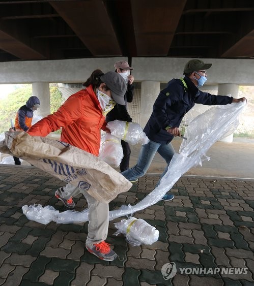 ▲ 25일 오전 경기도 파주시 임진강역 인근에서 마스크와 수건으로 얼굴을 가린 청년들이 보수단체의 대북전단 풍선을 빼앗은 뒤 칼로 찢고 있다.   ⓒ연합뉴스