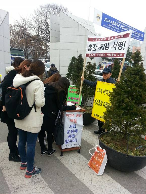 ▲ 11월 27일 총장 해임 서명에 학생들이 동참하고 있다. 배재흠 교수협 대표가 총장 해임 서명 팻말을 들고 1인 시위에 임하고 있다. ⓒ뉴데일리경제