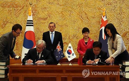 ▲ 박근혜 대통령과 토니 애벗 호주 총리가 배석한 가운데 지난 4월 8일 청와대에서 윤상직 산업통상자원장관과 앤드루 로브 통상투자장관이 한-호주 자유무역협정(FTA) 정식 서명식에서 협정서에 서명하고 있다. ⓒ연합