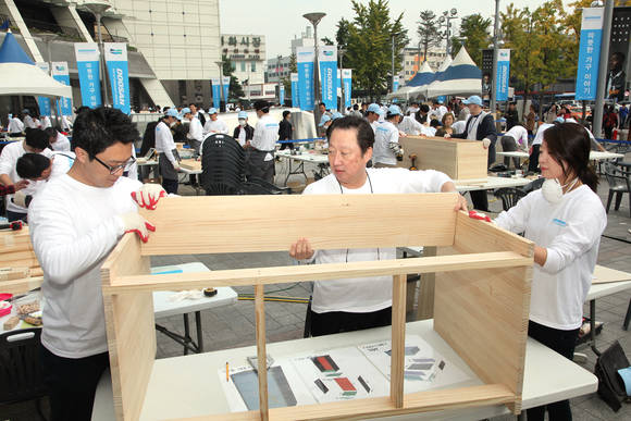 ▲ 박용만 회장<사진 가운데>과 두산 임직원 200여명이 '두산인 봉사의 날'을 맞아 서울 중구 을지로 두산타워 광장에서 저소득층 가정에 전달될 '가구 만들기' 작업을 하고 있다. ⓒ두산