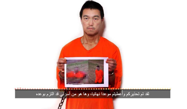 ▲ 테러조직 ISIS가 공개한 두 번째 협박 동영상. 고토 겐지 씨가 들고 있는 것은 유카와 하루나 씨가 참수된 사진이다. ⓒISIS의 협박 동영상 캡쳐