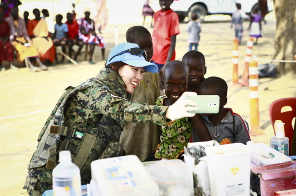 ▲ 한빛부대 간호장교가 의료 혜택을 받지 못하는 마을을 방문해 현지 아이들과 휴대폰으로 기념촬영을 하고있다.ⓒ합참