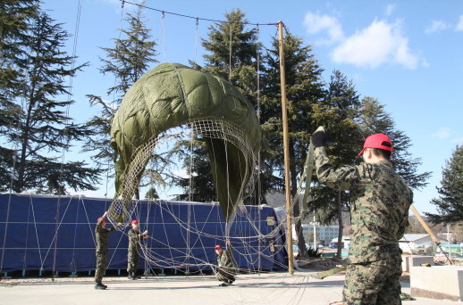 ▲ 장비정비중대 대원들이 낙하산 포장 전에 회수한 낙하산에 묻어   있는 먼지, 잡풀, 진흙, 나뭇가지 등을 털어내며 이상여부를 확인하고 있다.ⓒ육군 7공수특전여단