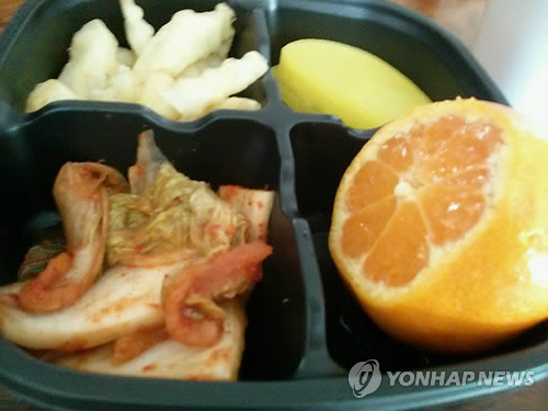 ▲ 천안시 홈페이지에 올라온 저소득층 초·중·고교생을 위한 점심 도시락. 천안시가 방학으로 점심을 먹지 못하는 저소득층 학생을 위해 배달하는 도시락으로 단무지 3조각, 김치 5-6조각, 감자튀김 7-8개, 잘려나간 귤 1개가 반찬의 전부다. 2013.1.15.ⓒ 사진 연합뉴스