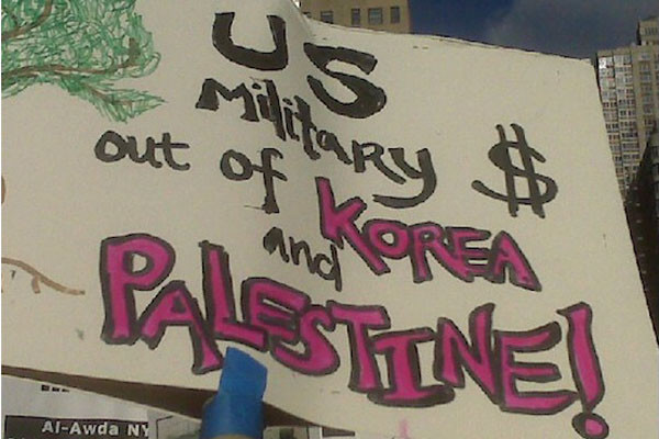 ▲ 재미종북단체들이 긴밀한 연대활동을 벌이고 있는 美막스레닌주의 단체 '앤서(ANSWER)'의 시위 장면 中 "팔레스타인과 한국에서 미군은 떠나라"는 피켓을 흔드는 장면. ⓒ재미종북성향 단체 '노둣돌' 홈페이지 캡쳐