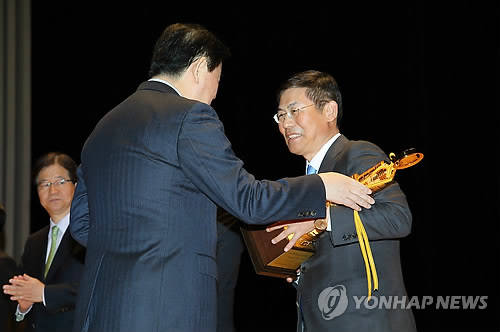 ▲ '제49회 납세자의 날' 행사에서 이상훈 삼성전자 사장(右)이 최경환 경제부총리 겸 기획재정부 장관으로부터 '국세 3조4000억원 탑'을 받고 있다. ⓒ연합