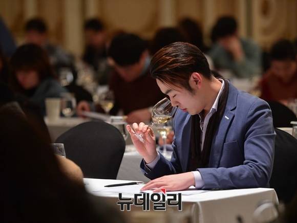 ▲ 한국 소믈리에 대회 1차 예선에서 한  참가자가 집중하며 와인의 향을 맡고 있다.