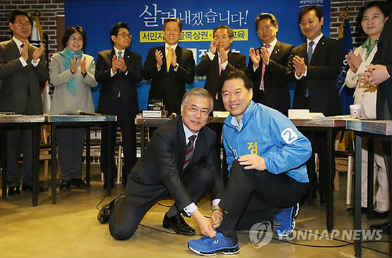 ▲ 새정치민주연합 문재인 대표가 30일 오전 보궐선거가 치러질 서울 관악을에서 연 현장최고위원회의에 앞서 이 지역에 출마할 정태호 후보에게 운동화를 신겨주는 퍼포먼스를 하고 있다. ⓒ연합뉴스 사진DB