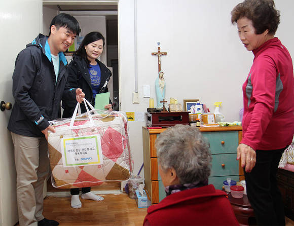 ▲ 서울 송파구내 저소득 독거 노인 가정을 방문한 삼표 자원봉사단원들이 봄 이불을 전달하고 있다. ⓒ삼표