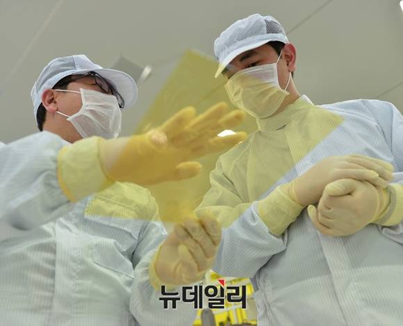 ▲ 비아트론의 열처리 장비를 통해 생산된 플렉시블 디스플레이를 살펴보고 있다.