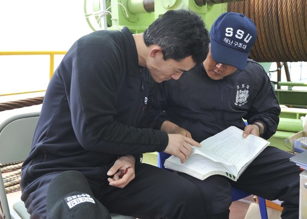 ▲ 세월호 구조 당시, 해군 해난구조대(SSU) 잠수사와 해경 특수구조단 잠수사가 잠수교범을 보며 탐색 및 구조작전에 대한 의견을 나누고 있다.ⓒ해군본부