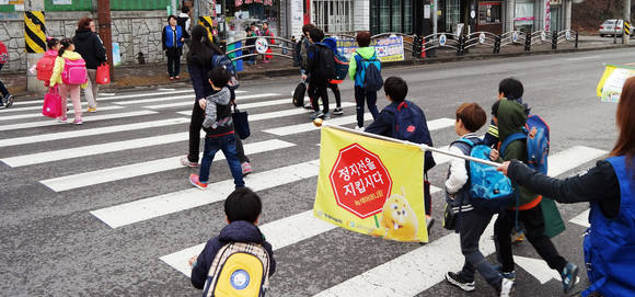 ▲ 쌍용자동차 서인천영업소 직원들이 15일 인천공촌초등학교 학생들을 대상으로 두다다쿵 캐릭터가 도안된 안전깃발을 활용하여 등굣길 캠페인을 진행하고 있다.ⓒ쌍용차