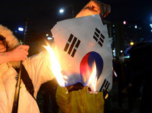 ▲ 18일 오후 광화문광장 인근에서 벌어진 세월호 폭력 시위 도중, 20대로 보이는 시위참가자가 태극기를 불에 태우는 모습. (ⓒ뉴스1 홈페이지 보도화면 캡쳐)