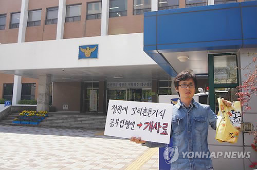 ▲ 박근혜 대통령을 비난하는 내용의 유인물을 제작한 자칭 시민활동가가, 출판물에 의한 명예훼손 혐의로 경찰 조사를 받던 중, 갑자기 조사를 거부하고 나간 뒤 해당 경찰서 정문에 미리 준비해 준 개 사료를 뿌리는 퍼포먼스를 벌였다. ⓒ 연합뉴스