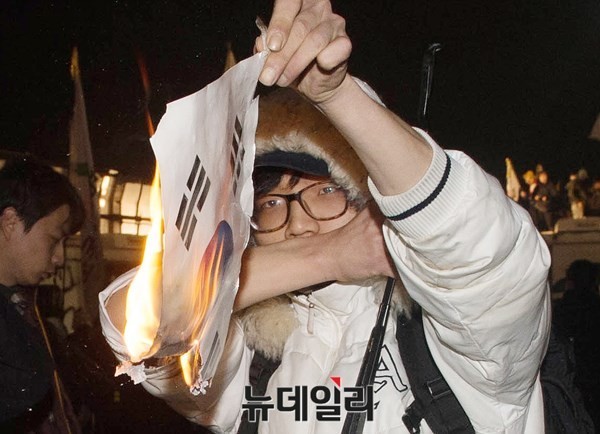 지난 18일 서울 광화문 일대에서 벌어진 세월호 폭력시위 당시 태극기를 불태운 방화범의 모습. ⓒ 뉴데일리DB