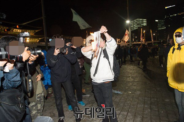 ▲ 지난 18일 서울 광화문 일대에서 벌어진 세월호 폭력시위 당시, 20대 남성으로 추정되는 인물이 태극기를 불태우고 있다. ⓒ 뉴데일리DB
