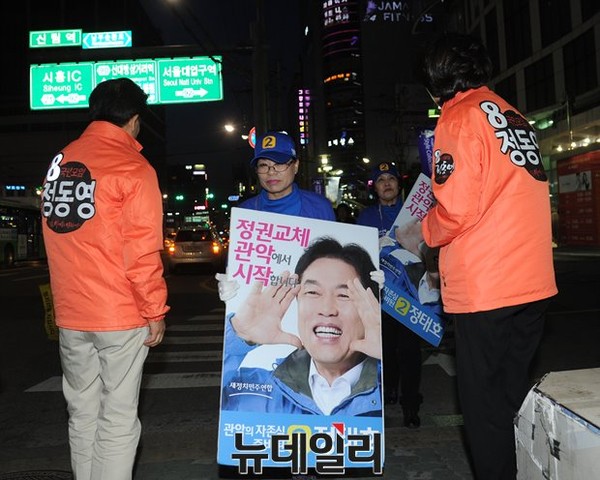 ▲ 국민모임 정동영 후보와 이행자 시의원이 유세를 진행하는 가운데, 새정치민주연합 정태호 후보 측 선거운동원들이 지나가고 있다. ⓒ뉴데일리 정재훈 기자