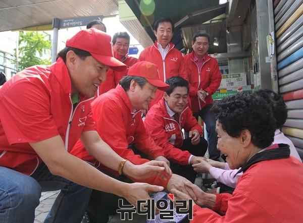 ▲ 새누리당 오세훈 전 서울시장과 김무성 대표최고위원, 오신환 후보(사진 왼쪽부터)가 26일 신원시장을 방문한 자리에서 길가에 앉아 있는 할머니들과 손을 맞잡고 있다. ⓒ뉴데일리 정재훈 기자