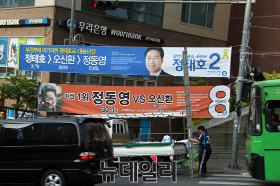 ▲ 관악구선관위가 26일 위법 여론조사 결과를 인용한 현수막에 대한 철거 명령을 내린 직후 새정치연합 정태호 후보 측에서 현수막을 철거하고 있다. ⓒ정동영 후보 선거사무소(톱데일리 제공)