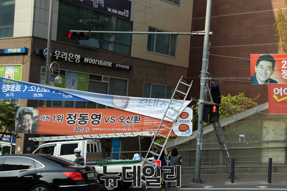 ▲ 관악구선관위가 26일 위법 여론조사 결과를 인용한 현수막에 대한 철거 명령을 내린 직후 새정치연합 정태호 후보 측에서 현수막을 철거하고 있다. ⓒ정동영 후보 선거사무소(톱데일리 제공)