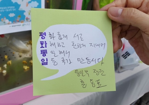 ▲ 홍용표 통일부 장관이 '통일박람회 2015' 개막 이튿날인 30일, '평화통일'이란 문구로 사행시를 만들어 달라는 부스 관계자의 요구에, 손글씨로  즉석에서 사행시를 지었다. ⓒ뉴데일리 이종현 기자