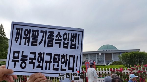 ▲ 대한민국어버이연합 소속 회원들이 1일 오후 서울 여의도 국회 앞에서, '끼워팔기 졸속입법! 무능국회 규탄한다' 등이 적힌 피켓을 들고, 국회법 개정안 날치기 통과를 규탄하는 집회를 열고 있다. ⓒ 뉴데일리 윤진우 기자