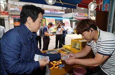 ▲ 22일 오전 수원의료원 인근의 정자시장을 방문한 남경필 경기도지사가 물품을 구입하고 전통시장 온누리 상품권으로 지불하고 있다. ⓒ경기도 사진제공