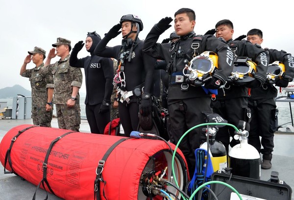 ▲ 사진은 서남해역의 해양재난 구조임무를 담당하는 해군 3함대의 구조작전대원들이 심해잠수사 복장을 갖추고 장비 앞에서 포즈를 취하고 있다. (앞쪽 적색 장비 : 이동형 1인용 감압챔버, 우측 장비 : 표면공급잠수시스템).ⓒ해군