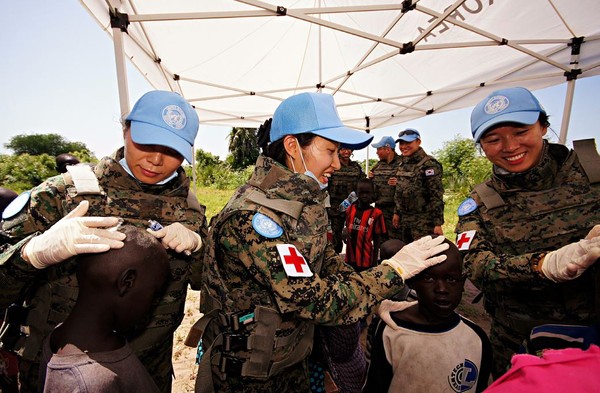 ▲ 한빛부대 간호장교들이 어린이들에게 피부연고를 발라주고 있다. 왼쪽부터 4진 최광선 대위, 5진 김지헤 대위, 4진 이미랑 대위.ⓒ국방부 공동취재단