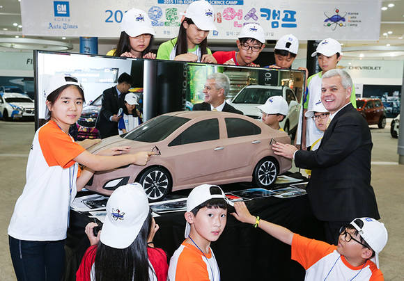 ▲ 28일 한국지엠 부평 본사 홍보관에서 진행된 오토 사이언스 캠프 입소식에서 한국지엠 세르지오 호샤 (Sergio Rocha) 사장이 이번 캠프에 참석한 학생들과 자동차 클레이 모형을 함께 살피며 담소를 나누고 있는 모습.ⓒ한국지엠