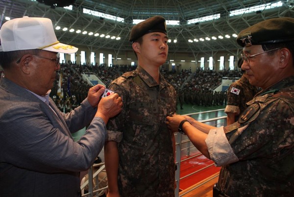 ▲ 6.25전쟁 참전용사인 송용호 옹이 손자인 송봉근 이병에게 태극기를 부착해주고 있다.ⓒ육군
