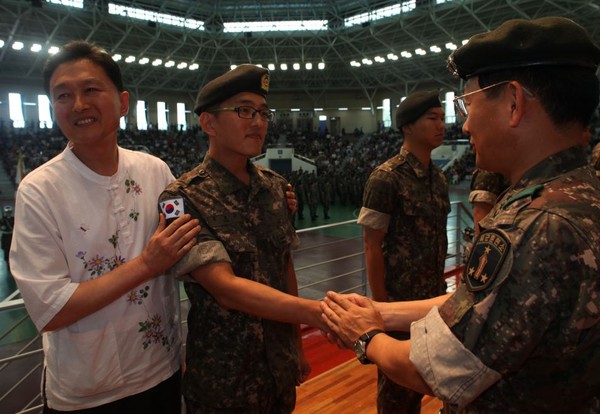▲ 윤호근 이병 아버지가 태극기를 부착해주고 있다.ⓒ육군