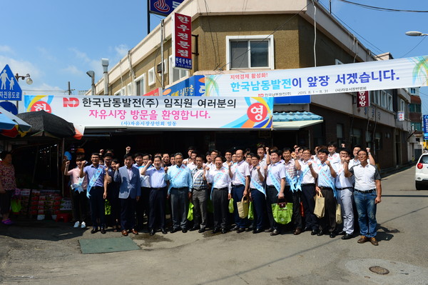 ▲ 남동발전 직원 50여명이 양손이 무겁게 전통시장 물품을 구매하고 포즈를 취하고 있다