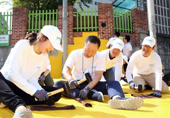 ▲ 박용만 두산그룹 회장(왼쪽 2번째)이 서울 중구 신당초등학교에서 임직원들과 함께 어린이들의 안전한 보행을 돕기 위한 안전지대인 '옐로카펫'을 부착한 후 잘 붙도록 고무망치로 두드리고 있다. ⓒ두산